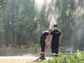 Strażacy z wążem strażackim podczas pokazu lania wody
