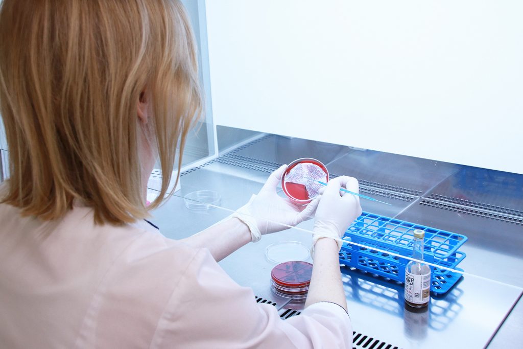 Zdjęcie przedstawia laboranta wykonującego badanie mikrobiologiczne